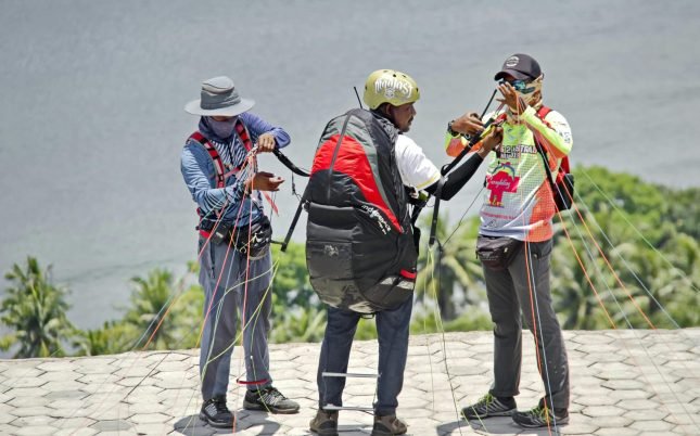 Team preparing for a thrilling paragliding adventure with safety checks and equipment setup.